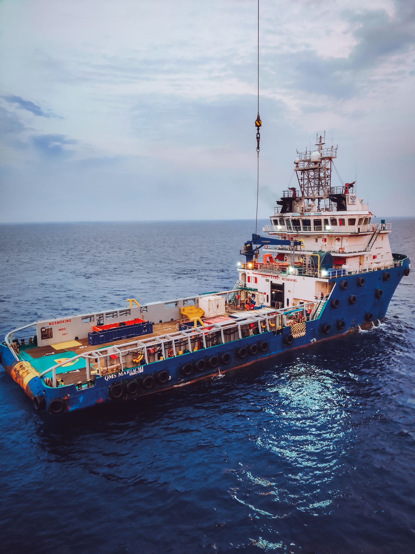Offshore supply vessel holding position beneath a platform crane hook